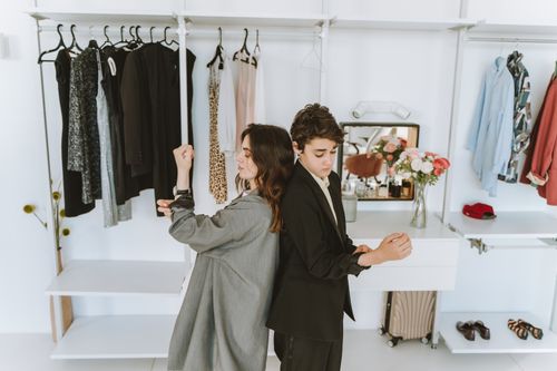 Free A mother and son dressed in black and gray suits, stand back to back in a stylish wardrobe setting. Stock Photo