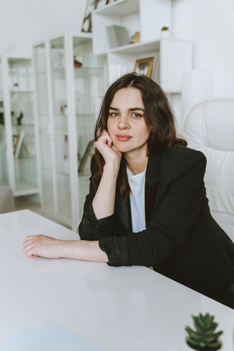 A Woman In Black Blazer Sitting On White Chair