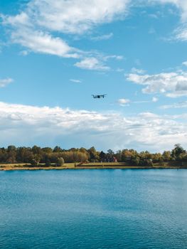 Drone flying over a tranquil lake in Reigate, England with clear blue skies and lush green trees.