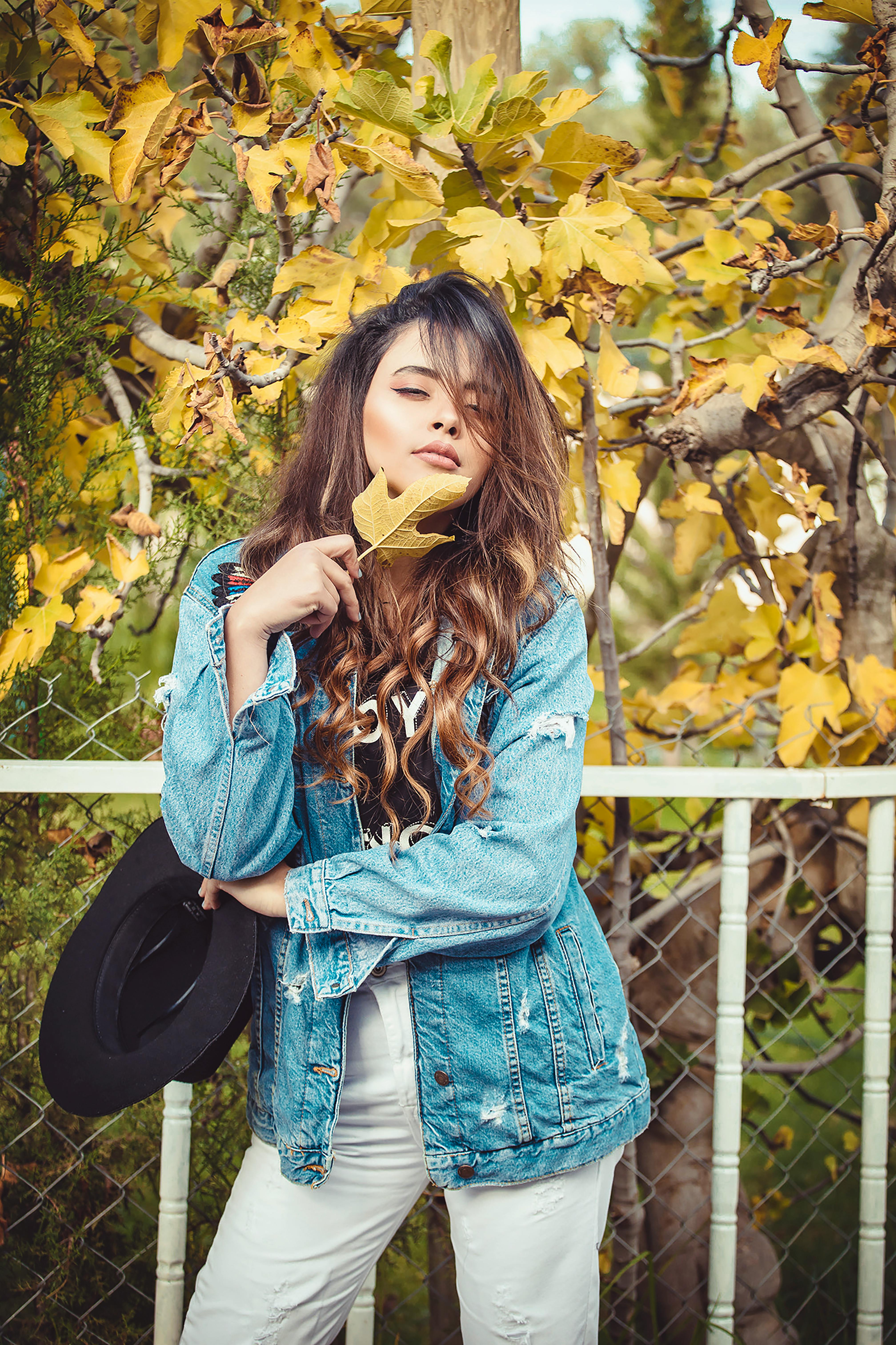 Stylish young girl in trendy casual clothes in a denim jacket and headband  poses in the street on a Stock Photo by leikapro