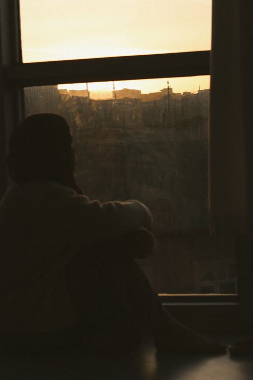Free A contemplative silhouette of a woman sitting by a window, observing a stunning sunset in Samsun, Türkiye. Stock Photo