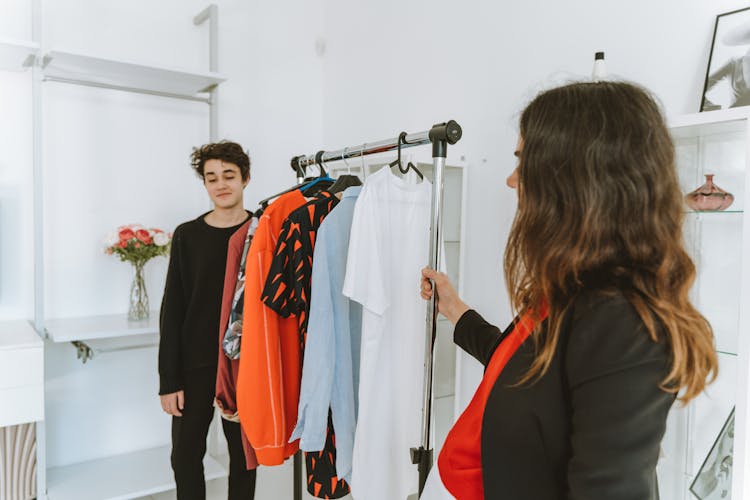 Woman And A Young Man Standing Beside A Clothes Rack