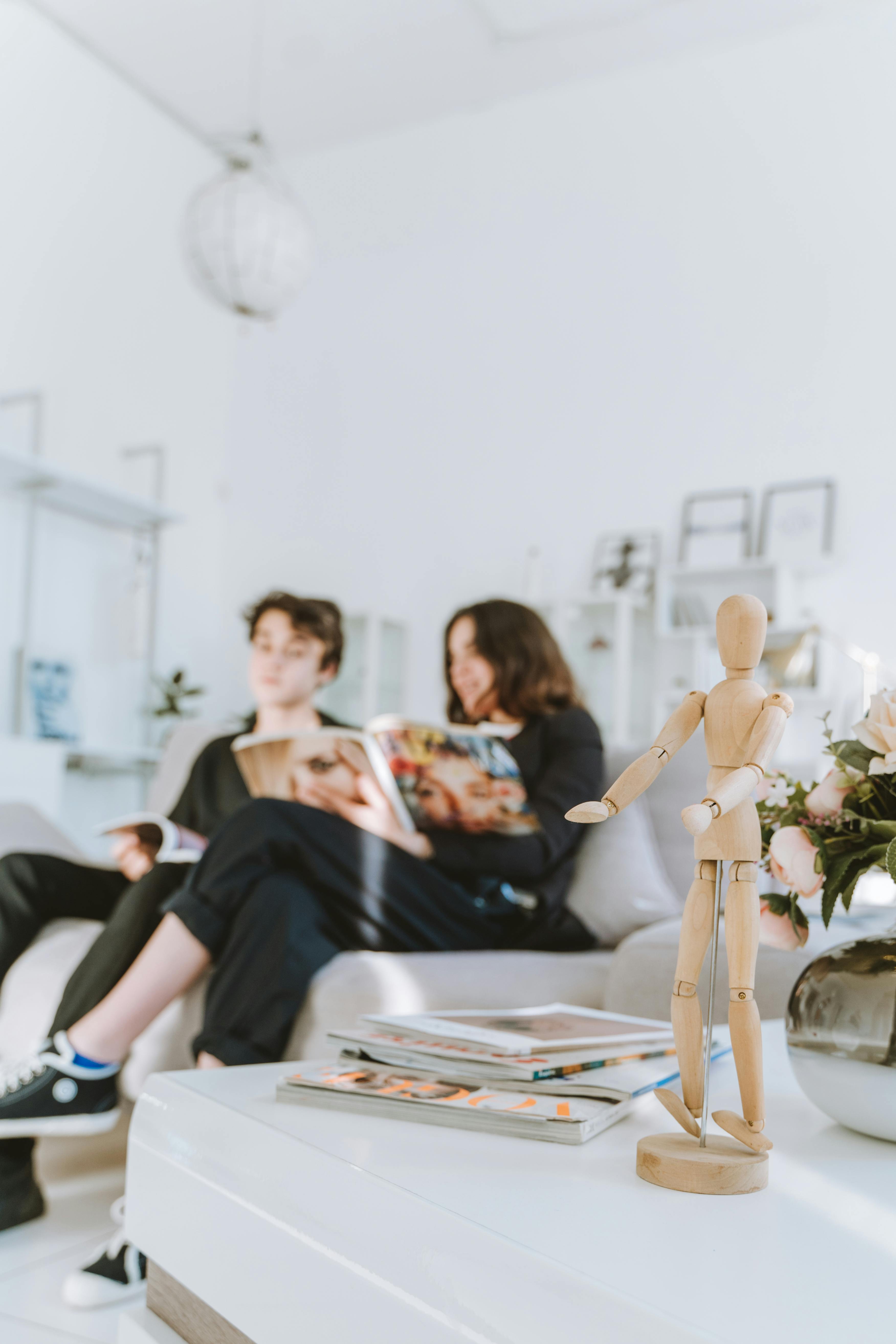 young man and woman sitting on sofa looking on a magazine