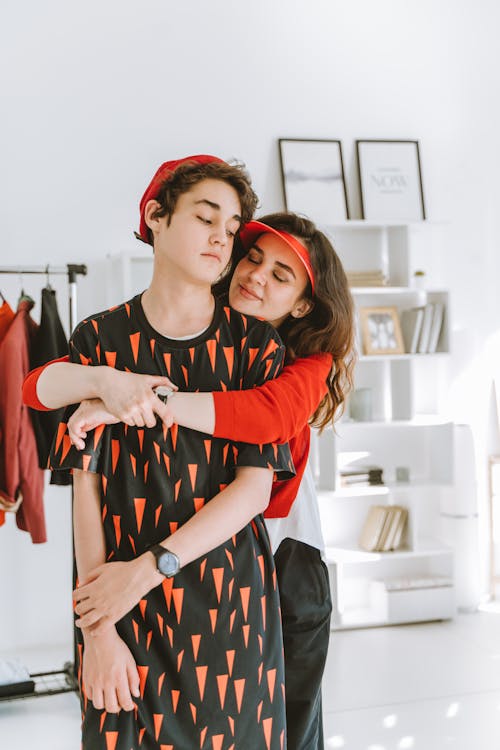 Woman in Red Long Sleeve Shirt Hugging a Young Man