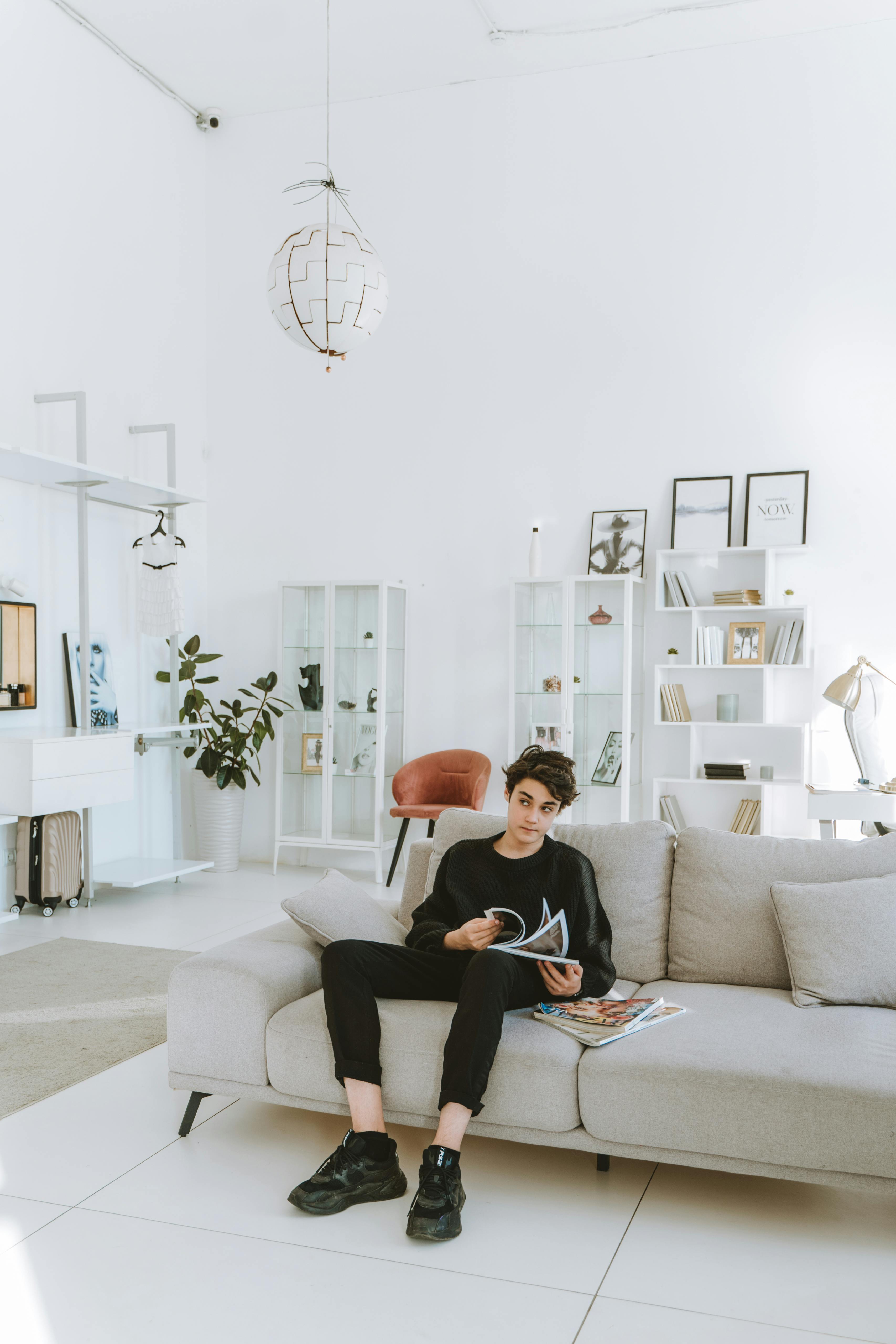 a young boy in black clothes sitting on the couch