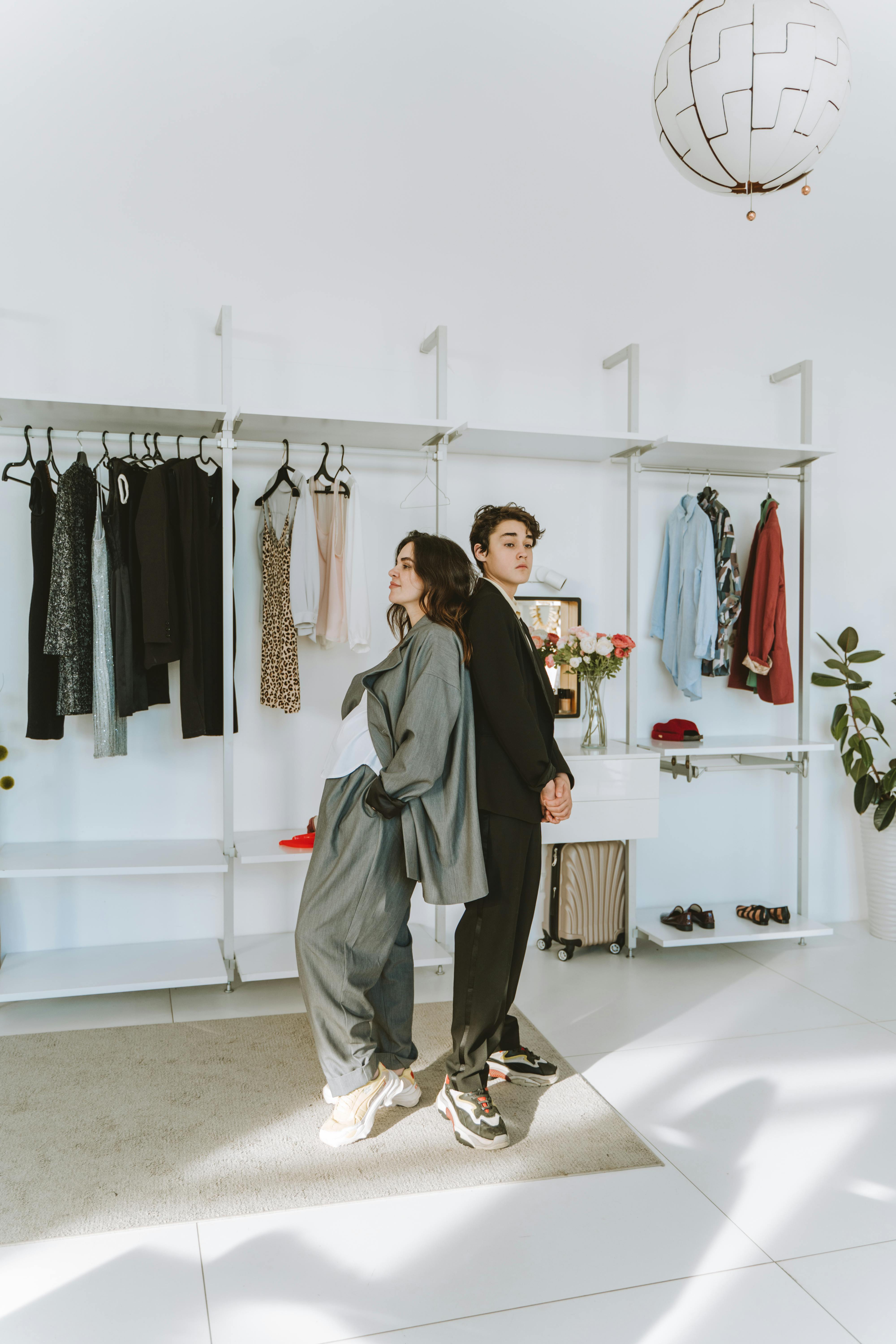 a woman in gray blazer standing back to back with the boy in black long sleeves