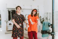 Woman in Black and White Floral Dress Standing Beside Woman in Red Long Sleeve Shirt