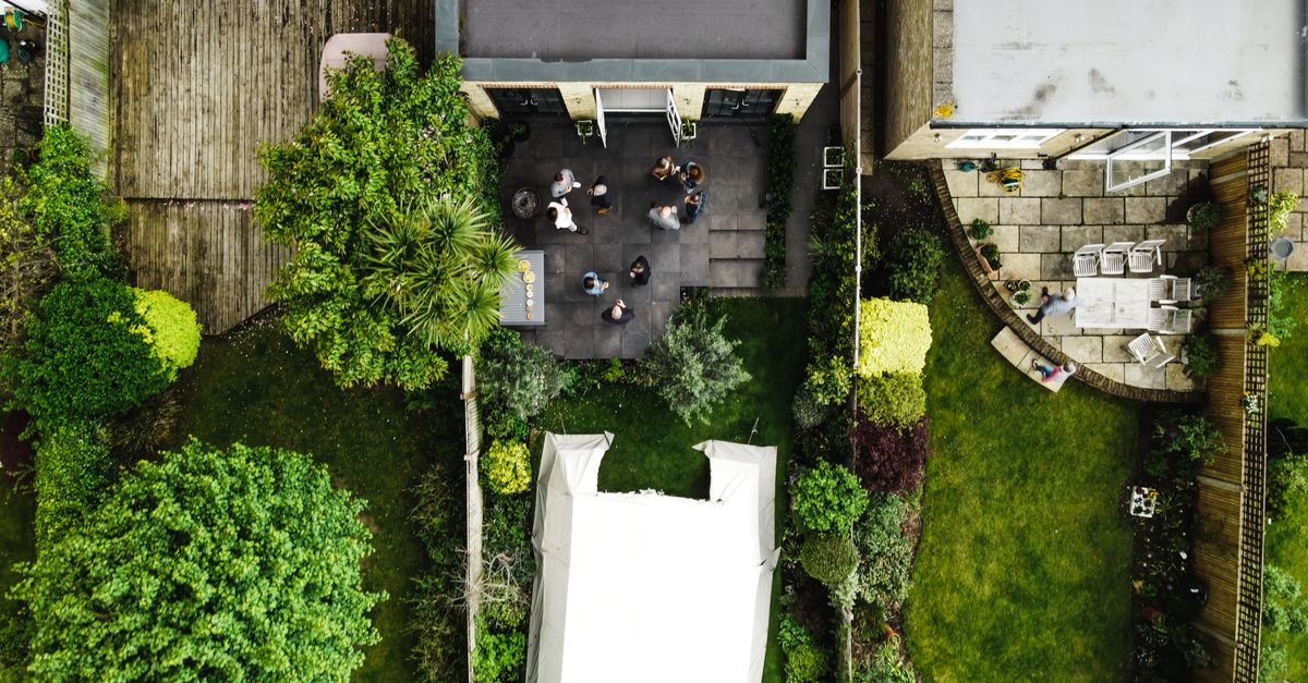 Drone shot of backyard gathering in England, showcasing garden and people.