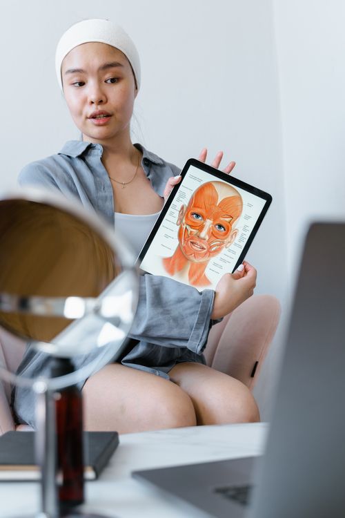 Free Young woman explaining skin care using an anatomy chart on a tablet during a therapy session. Stock Photo