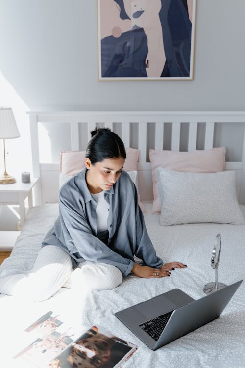 Woman sitting on Bed looking at a Laptop 