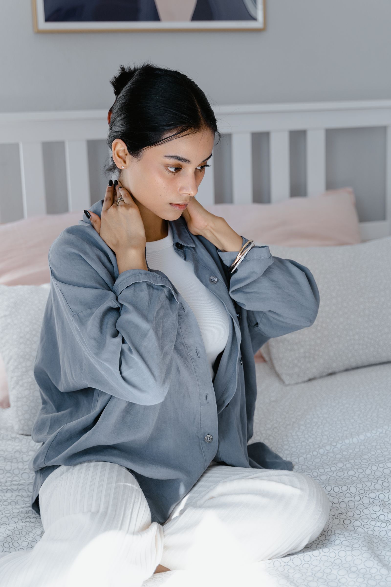 Person sitting on a bed holding the neck, matching cervical collar sleeping and night neck support guidance