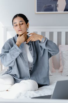 A serene woman applying skincare while sitting in a cozy bedroom setting, promoting self-care and relaxation.