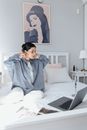 Woman in Gray Robe Sitting on Bed