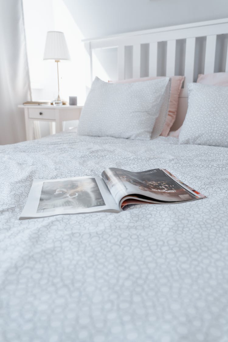 A Magazine On White Bed Linen