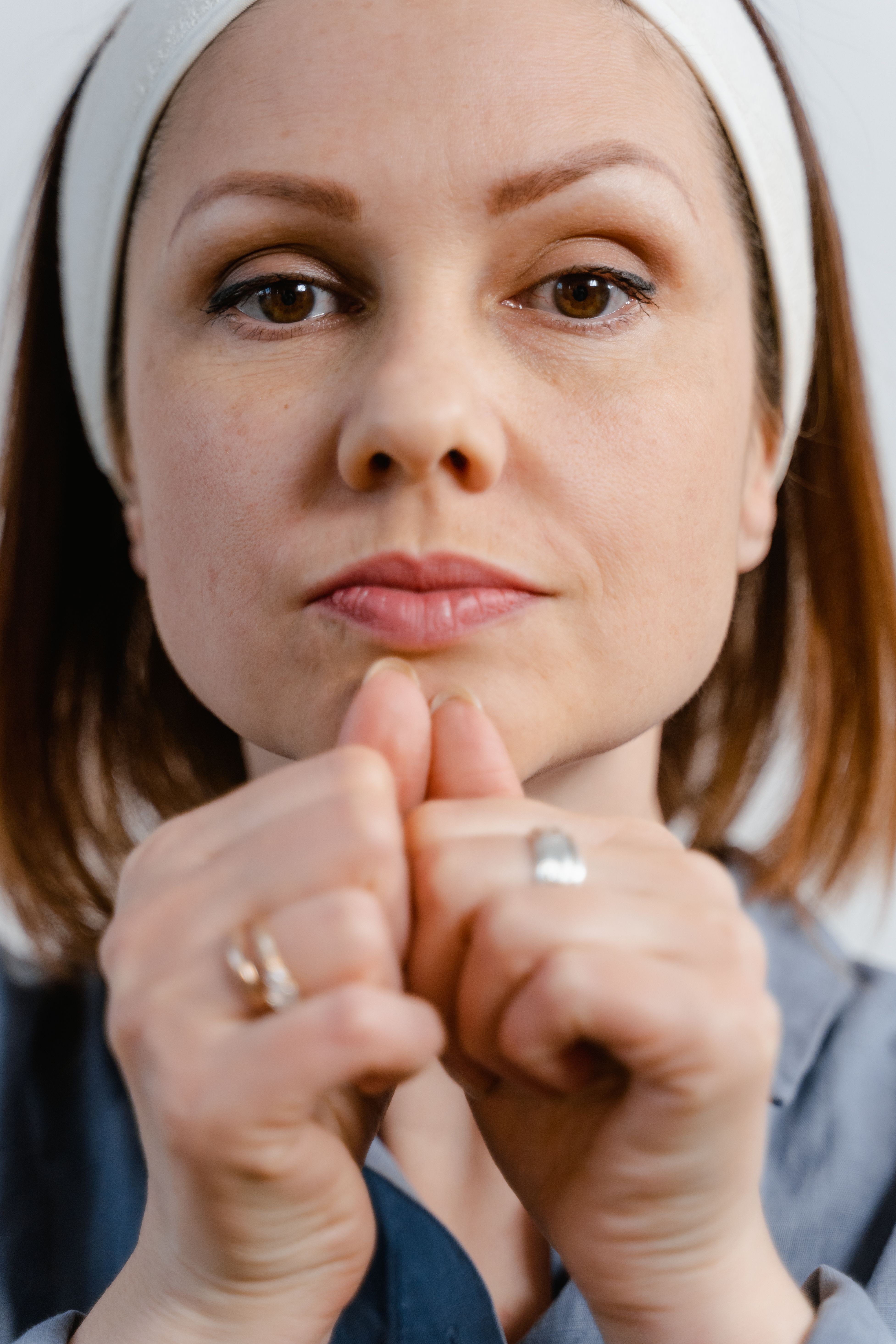 Detailed close-up portrait of a woman with rings, expressing contemplation.