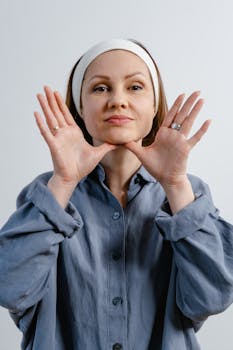 Woman performing facial massage with hands on chin, wearing headband.