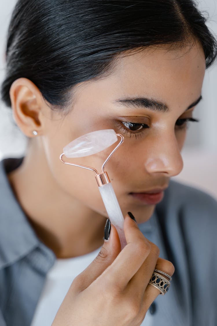 A Woman Using A Face Roller 