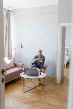 Asian woman applying skincare products at home in a cozy living room setting.
