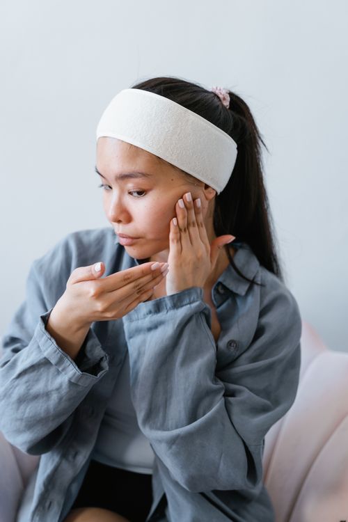 Free Young woman applying skincare product indoors, promoting healthy skin routine. Stock Photo