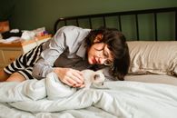 Woman in Gray Long Sleeve Shirt Lying on Bed With White Cat