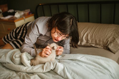 A Woman Petting a Kitten in Bed