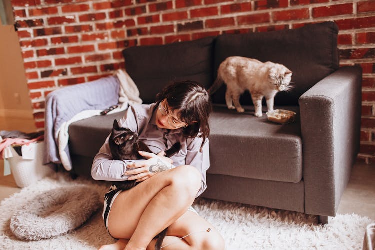 A Woman Petting Her Cats At Home