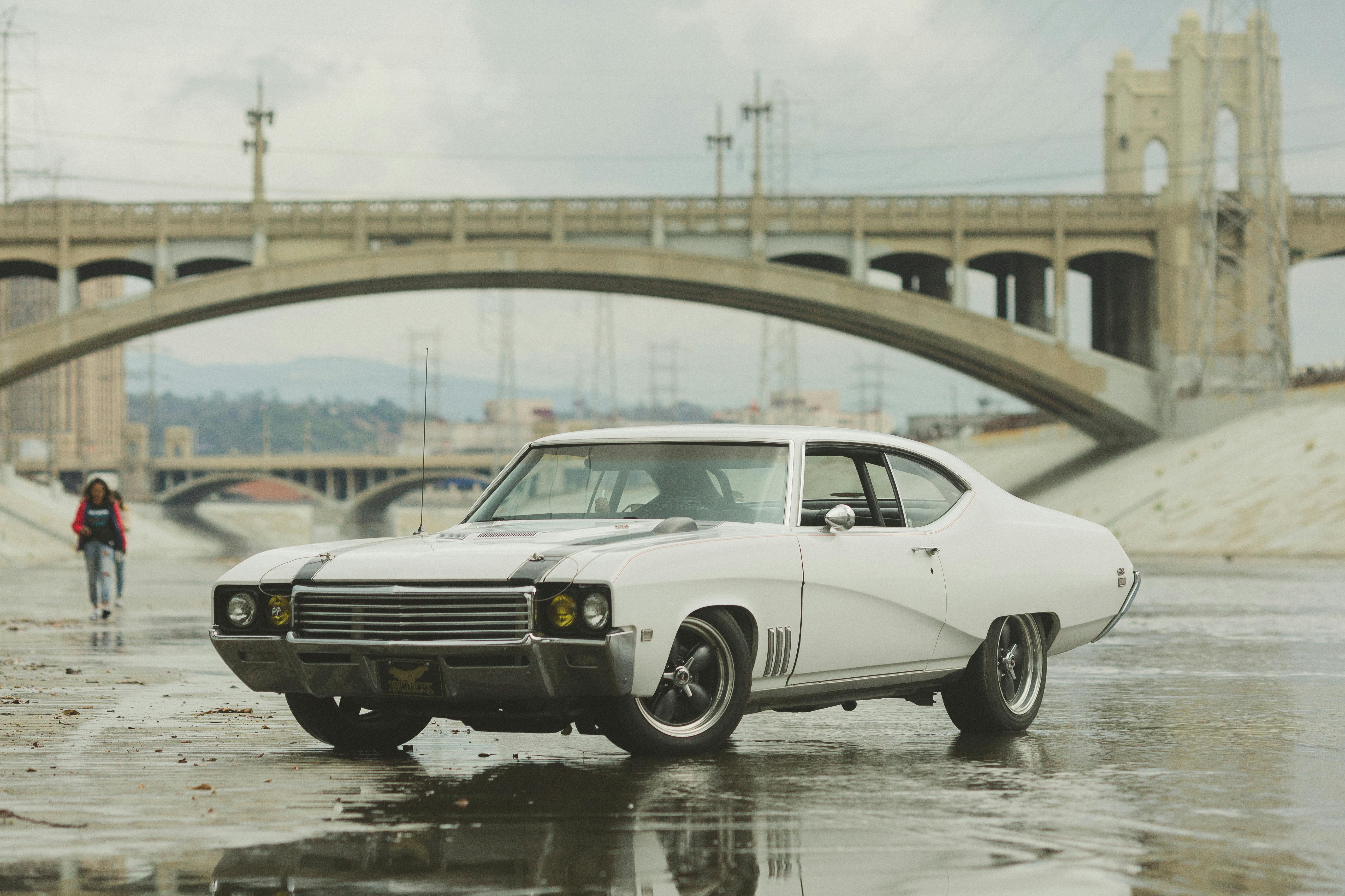 white coupe on body of water near bridge