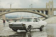 一辆经典的白色肌肉车停在桥边，展现了复古汽车的设计风格