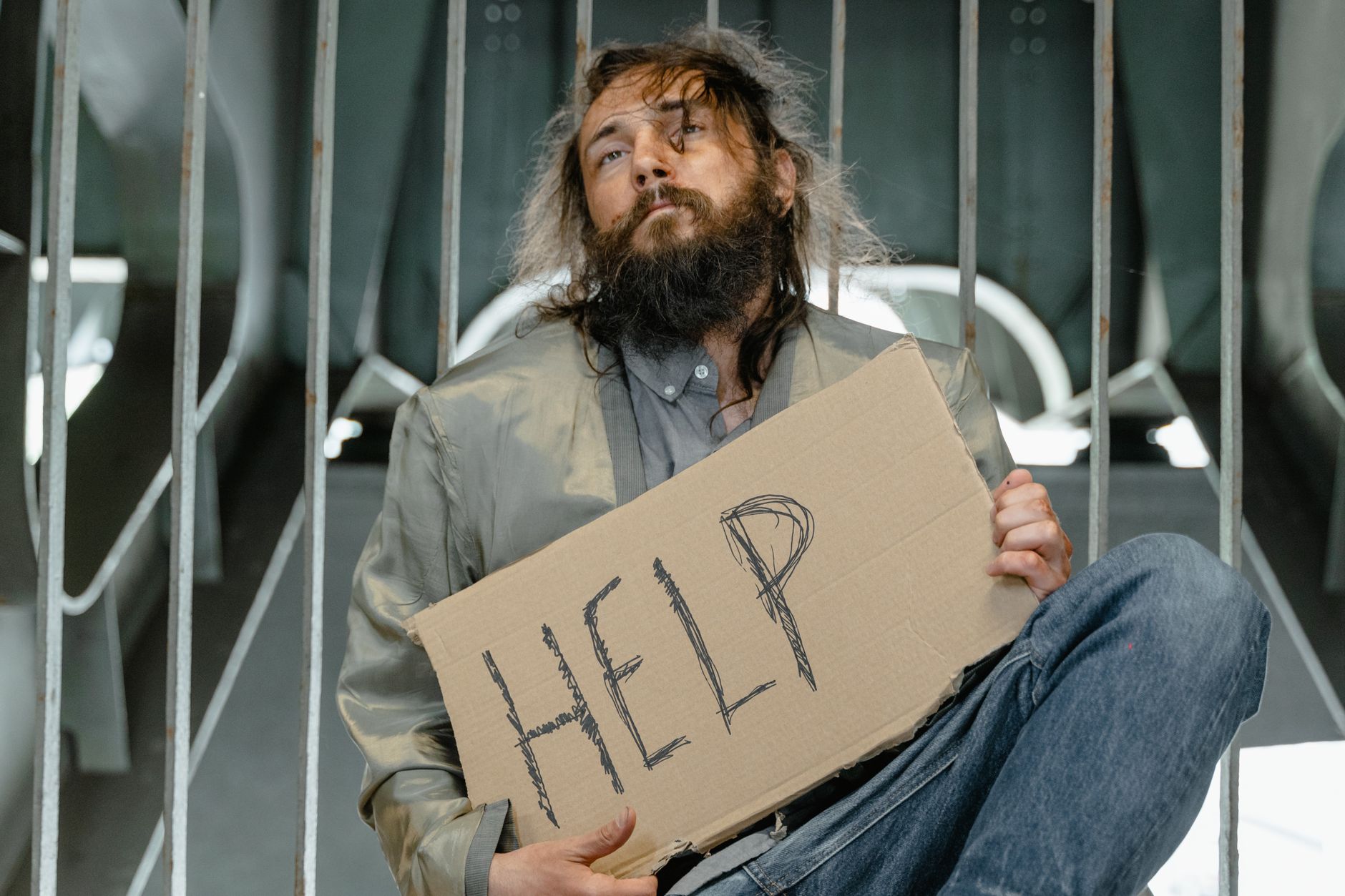 실업급여 예상 수령액 계산기 2 A homeless man with a beard holding a sign asking for help indoors.