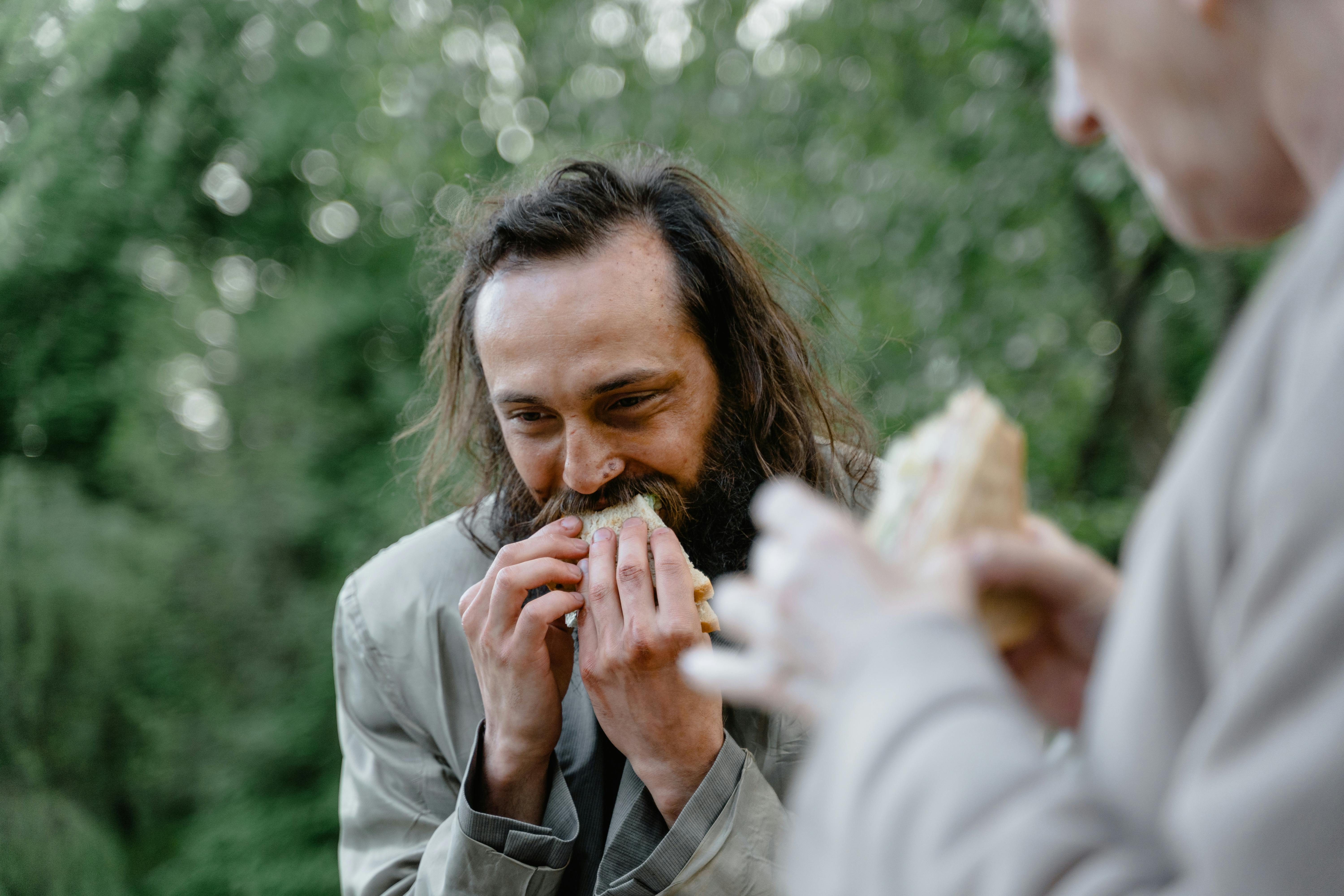 homeless man eating sandwich