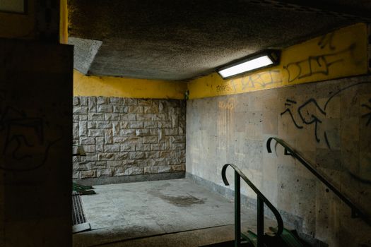 Moody image of a dimly lit, graffiti-covered underground passage showing urban decay.