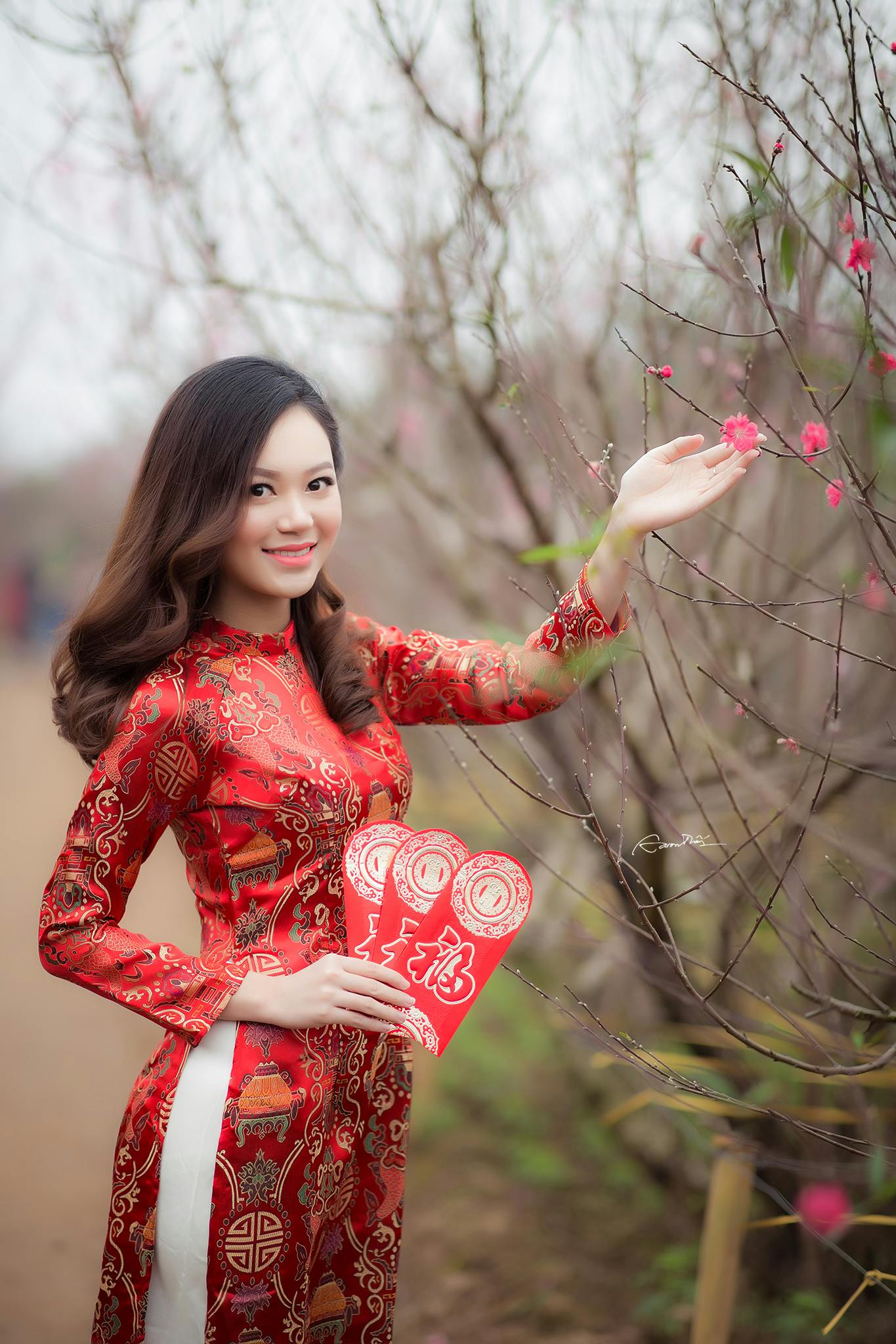 woman wearing red long sleeved dress holding pink petaled flower