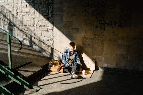 Free A homeless person sitting in a sunlit urban area, highlighting social issues. Stock Photo