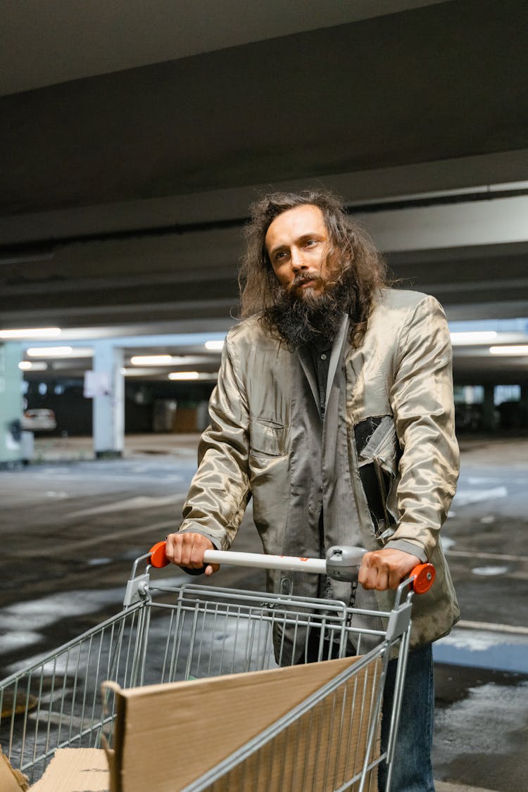 A Homeless Man Holding A Shopping Cart 