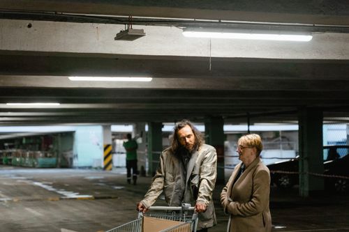 Free Two adults interacting in a dimly lit urban parking garage scene. Stock Photo
