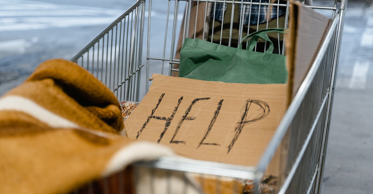 Photo by MART PRODUCTION A shopping cart with a cardboard 'Help' sign and belongings, symbolizing urban homelessness.