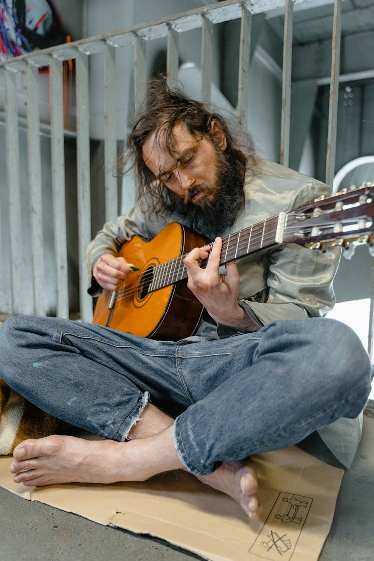 Man In Denim Jeans Playing A Brown Guitar