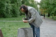 Homeless Man picking up Leftovers on a Trashbin
