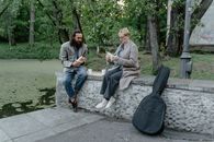 Man and Woman Sitting on Concrete Bench Near Trees
