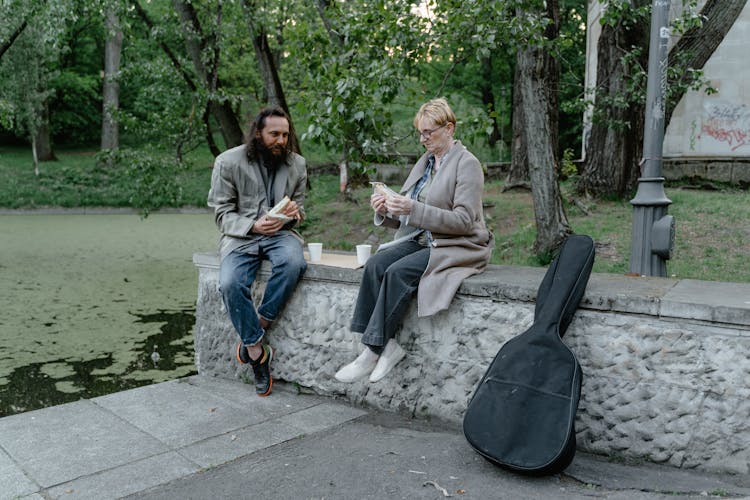 Two Homeless People Eating Sandwich Together