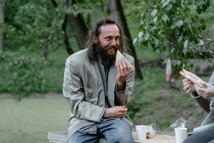 A Man Eating Sandwich On The Park Bench