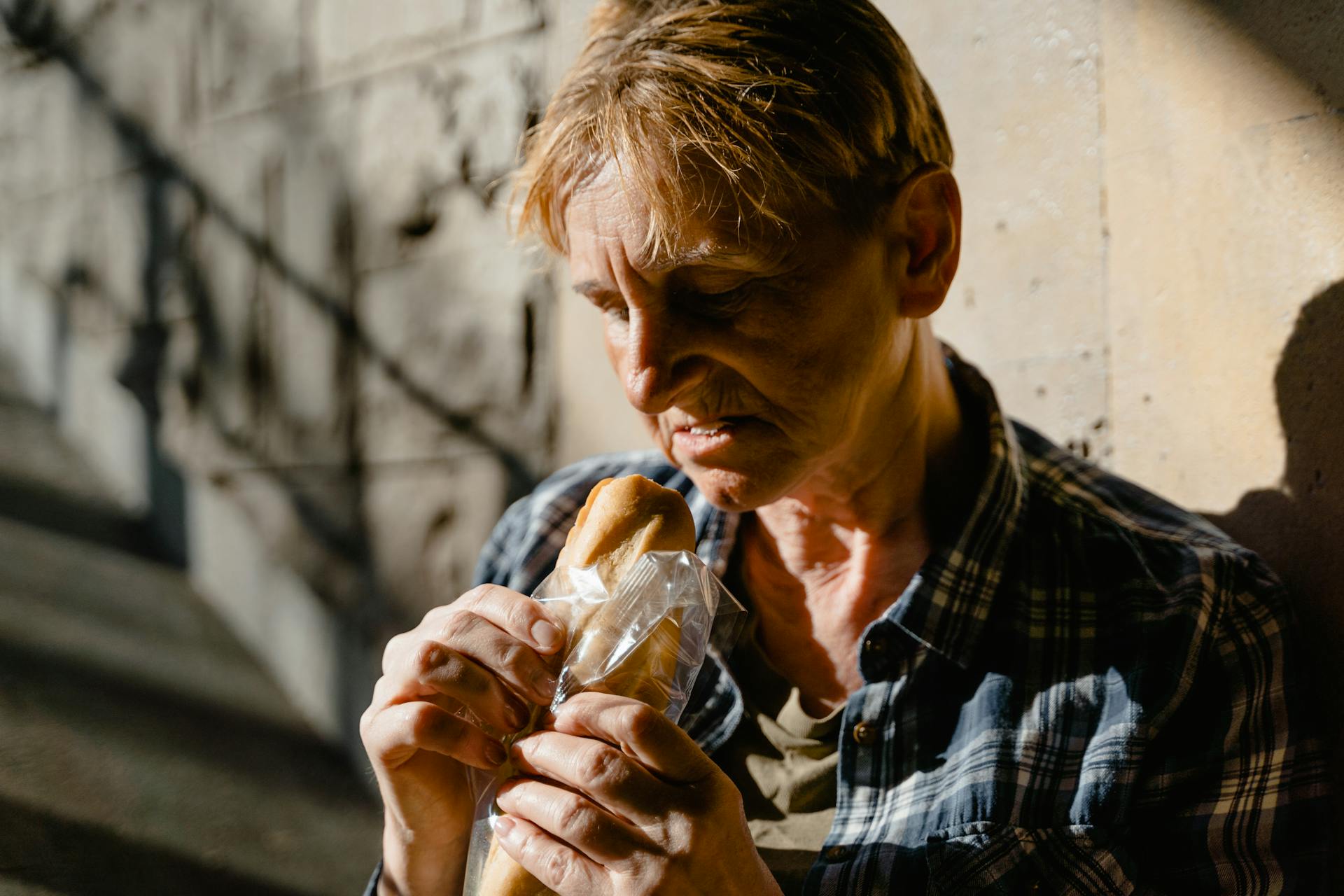 Close-up Photo of a Hungry Homeless Elderly Woman eating Sandwich