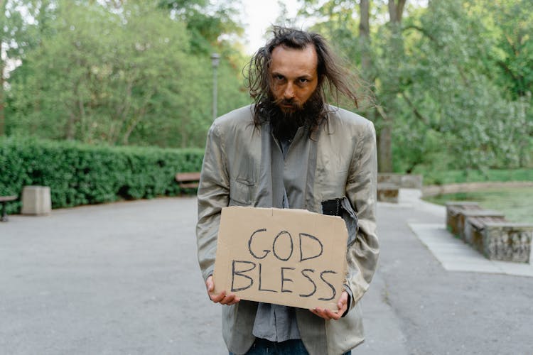 A Homeless Man Holding A Sign