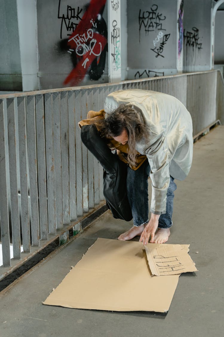 Barefooted Person Picking Up The Cartons On The Ground  
