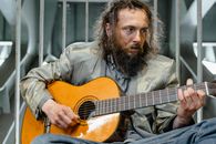 Man in Brown Jacket Playing Guitar