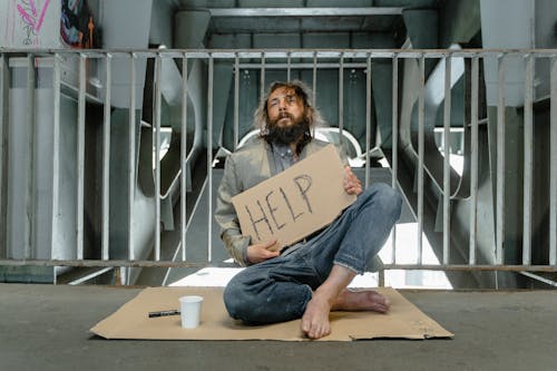 Tired and Hungry Homeless Man holding a Placard