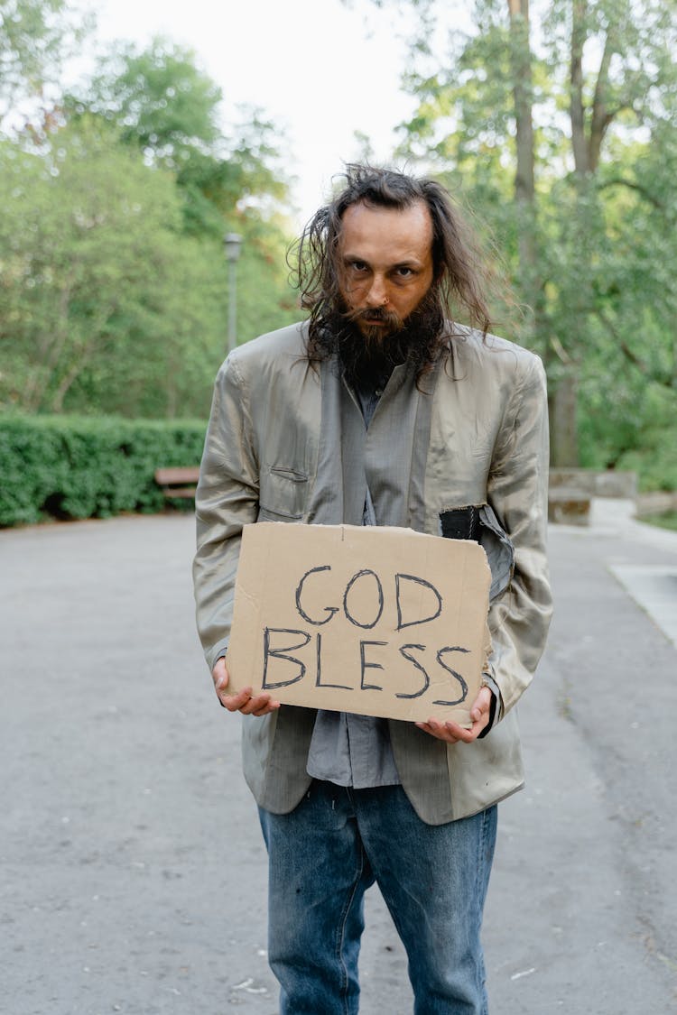 A Man Holding A God Bless Placard