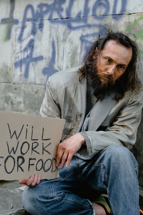 Free Tired and Hungry Homeless Man holding a Placard Stock Photo