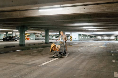 Free A Woman Pushing Her Car in the Parking Area Stock Photo