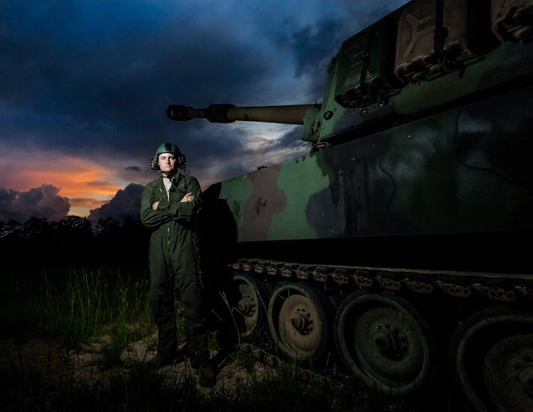 A Military Man Standing Besides A Tank